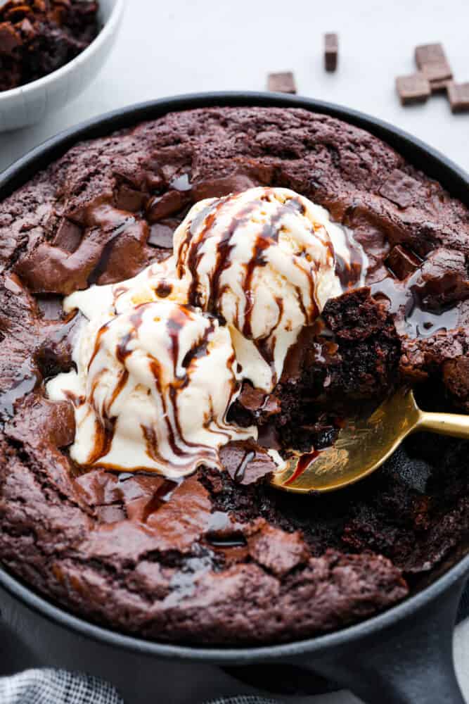 आइसक्रीम और चॉकलेट सॉस के साथ सबसे ऊपर एक स्किलेट ब्राउनी की हीरो इमेज।