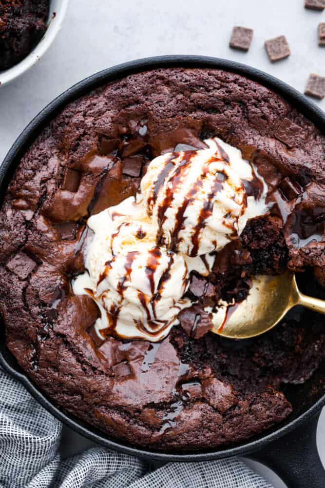 Brownies cooked in a skillet, topped with vanilla ice cream.