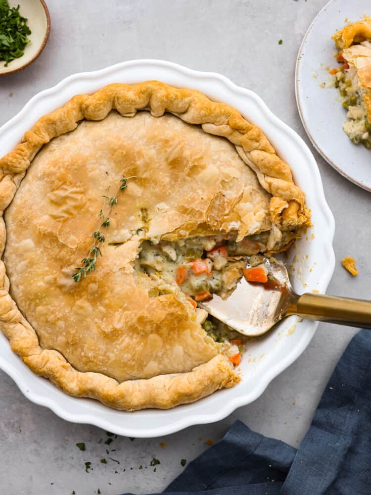 Beautiful chicken pot ipe with a slice taken out of it in a white pie dish.