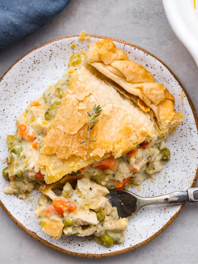 A slice of chicken pot pie on a plate with some on a fork.
