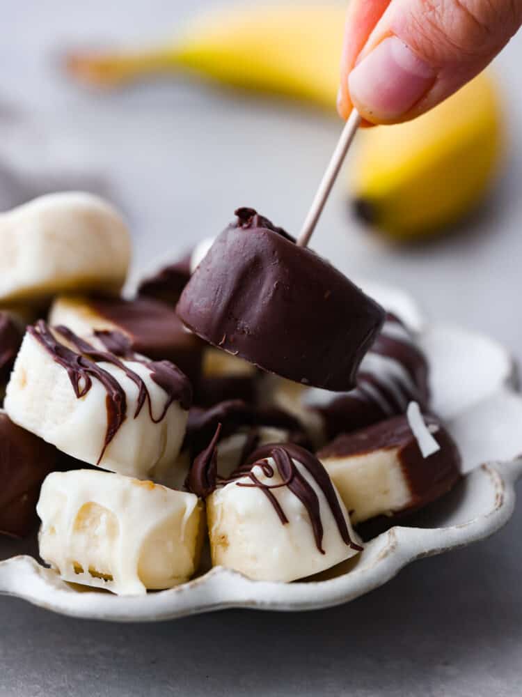 초콜릿으로 덮인 바나나를 이쑤시개로 집어들기.