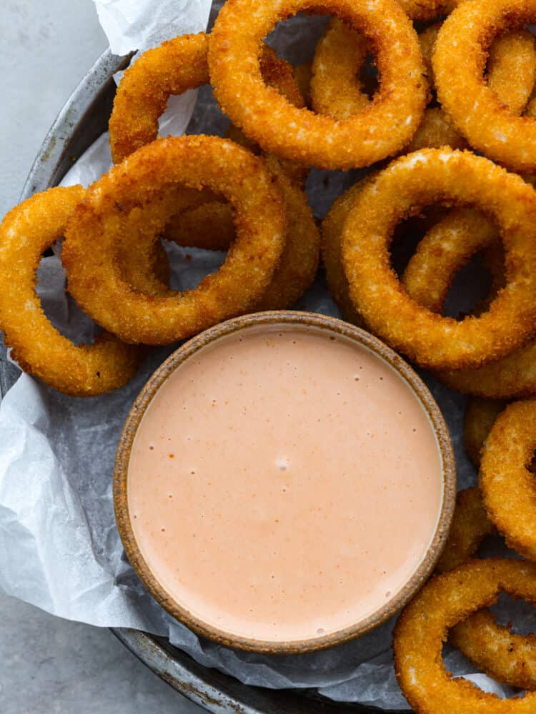 Top-down view of comeback sauce served with onion rings.