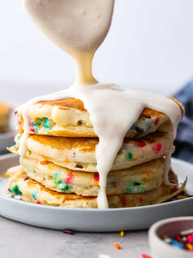 Glaze being poured on top of the funfetti pancakes.