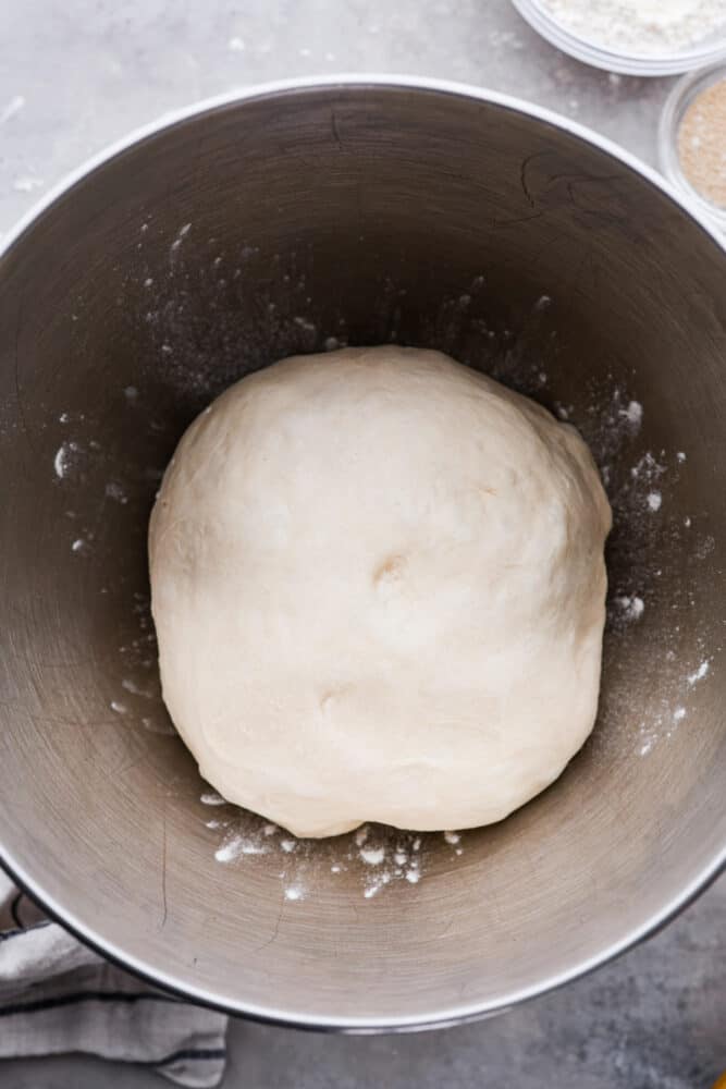 Pizza dough in a metal bowl.