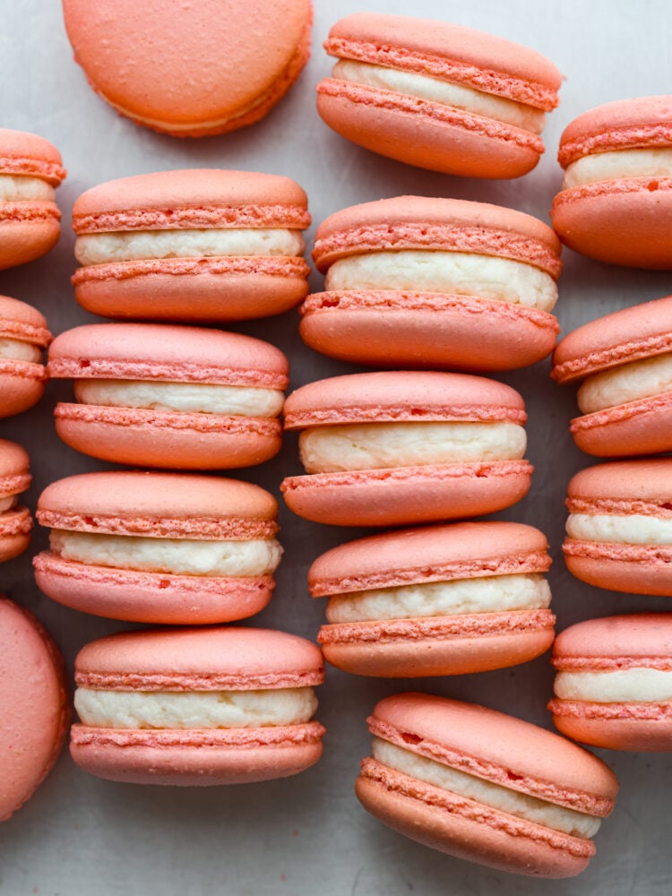 Macarons on a table stacked up next to each other with white frosting.