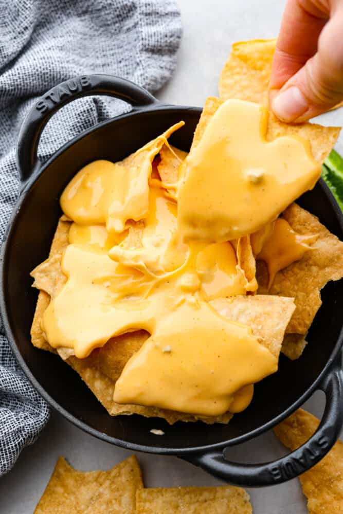 Nacho cheese sauce in a skillet over tortilla chips.