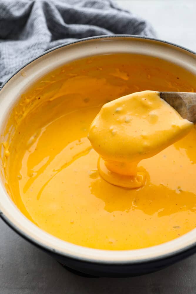 Cheese sauce in a pot with a wooden spoon.