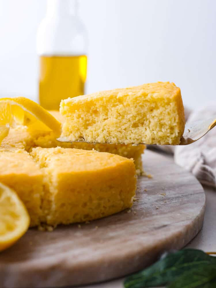 A slice of olive oil cake being picked up with a cake spatula.