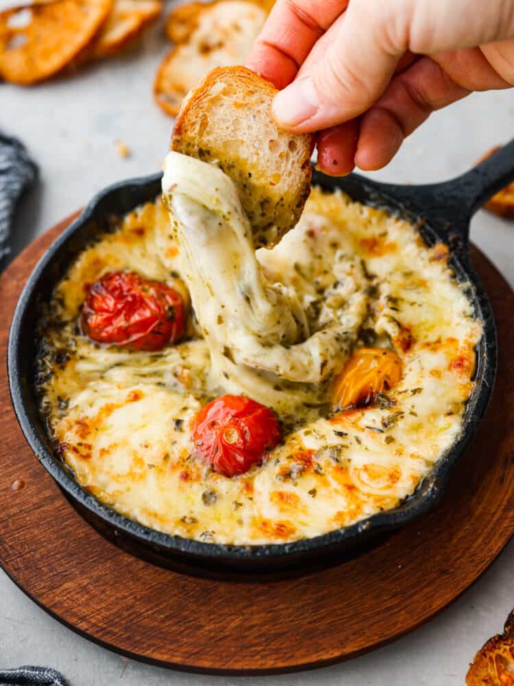 Baked provolone and grape tomatoes in a small cast-iron skillet.