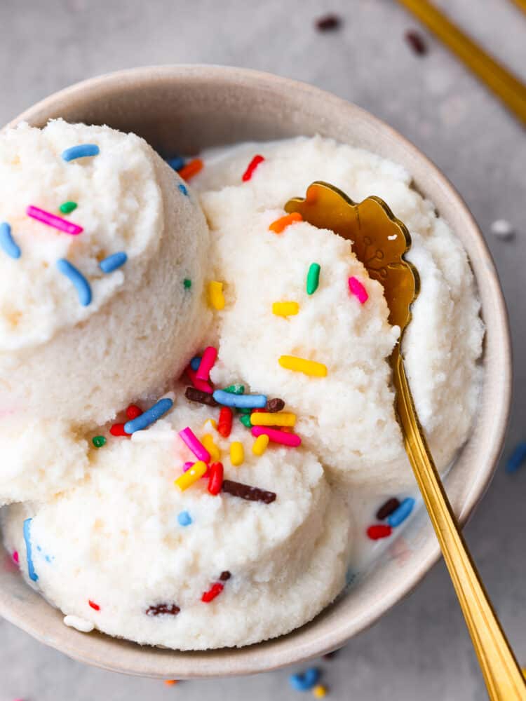 Snow ice cream in a bowl with sprinkles and a golden spoon.