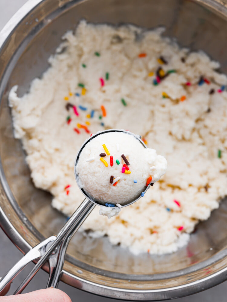Snow ice cream in a bowl being scooped out with a cookie scoop.
