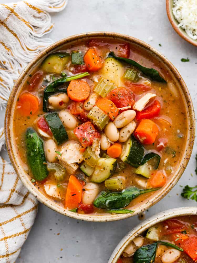 Tuscan vegetable chicken soup served in a stoneware bowl.