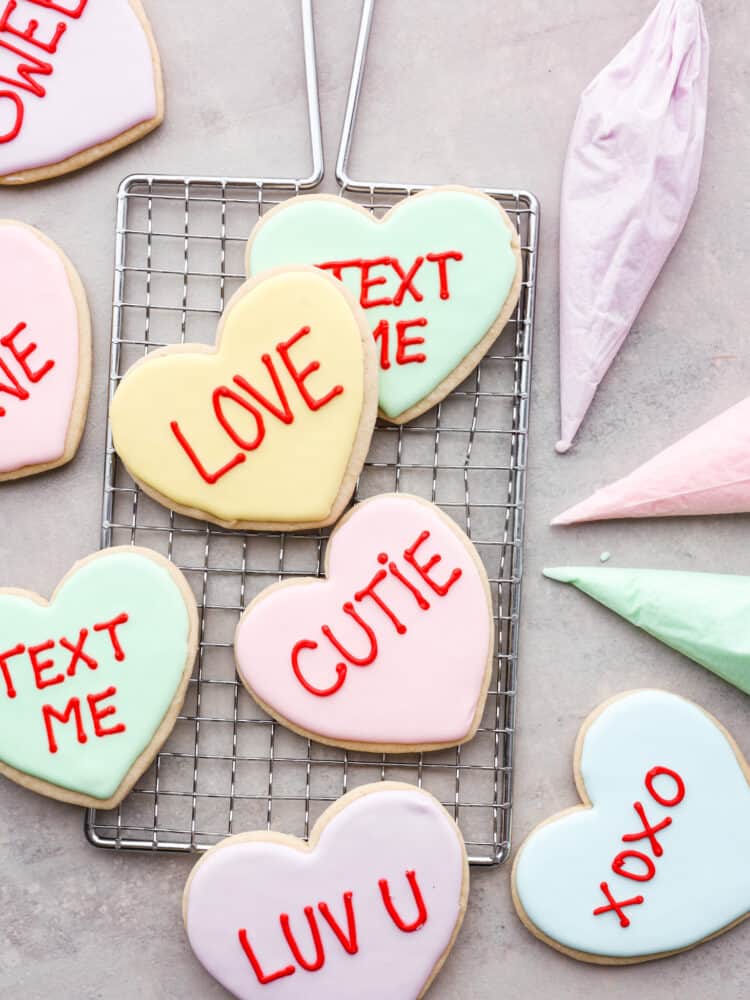 Valentine's day cookies on a cooling rack with fun sayings on them like "text me" and "cutie".