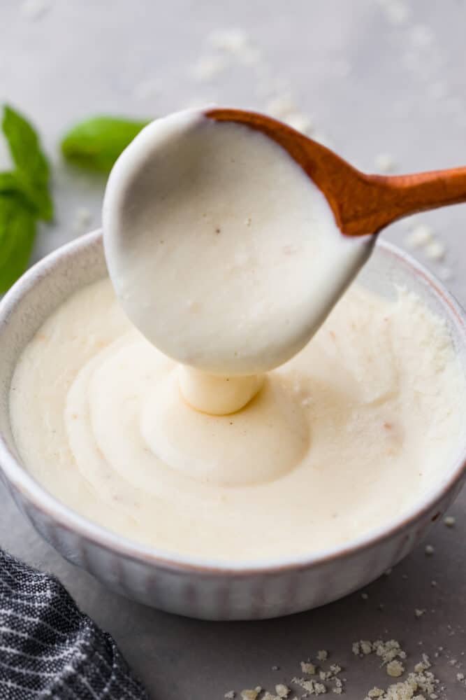 White pizza sauce on a wooden spoon.