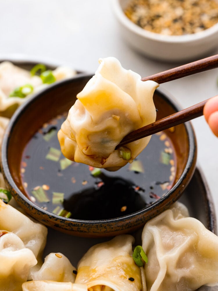 A pork wonton stuff dipped in sauce with chopsticks.