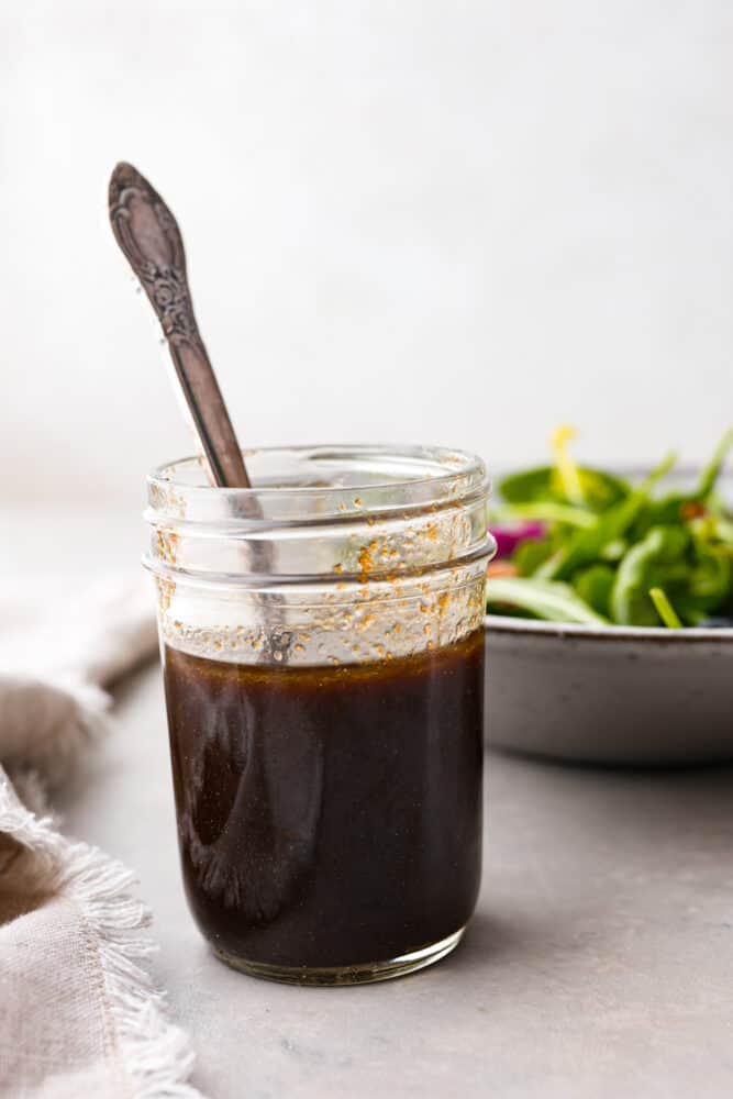 Balsamic vinaigrette in a mason jar with a spoon in it.