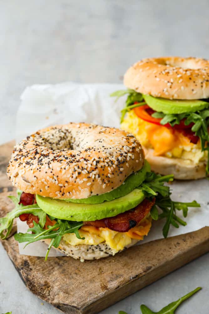 Bagel breakfast sandwiches on a cutting board.