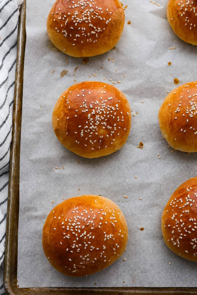 Brioche buns on a baking sheet.