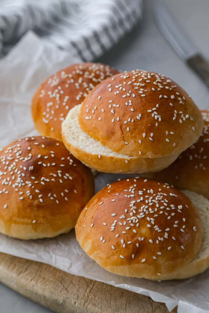 Brioche buns stacked on top of a cutting board.