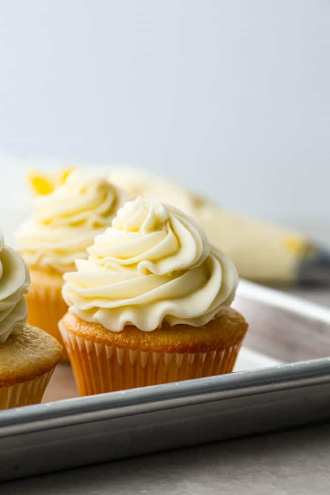 Imagen de héroe de un cupcake de pastel amarillo glaseado con crema de mantequilla.