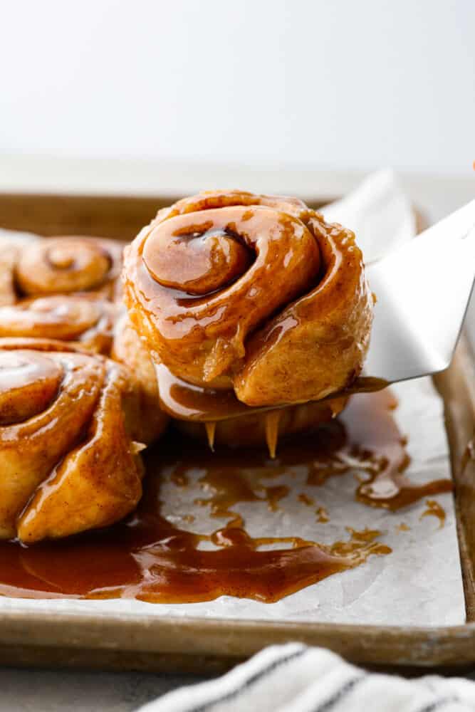 Caramel roll being lifted off parchment.