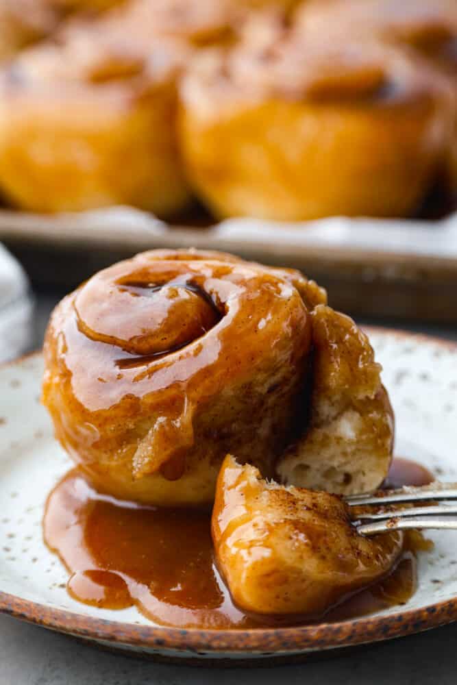 A caramel roll on a plate with a fork.