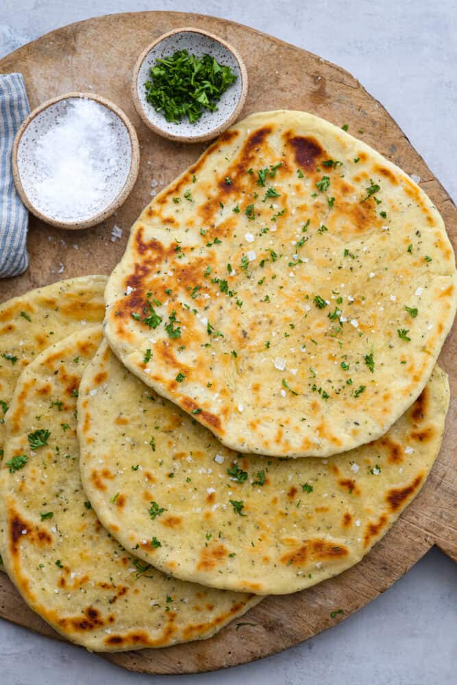 No Yeast Flatbread is a quick and easy bread recipe that you'll be making for years to come! Use it for sandwiches, gyros, pizza, and so much more. No need to wait for this bread to rise, with no yeast and cooked over the stove, it's a simple recipe that you will want to save for later. Flatbread on a wooden board.