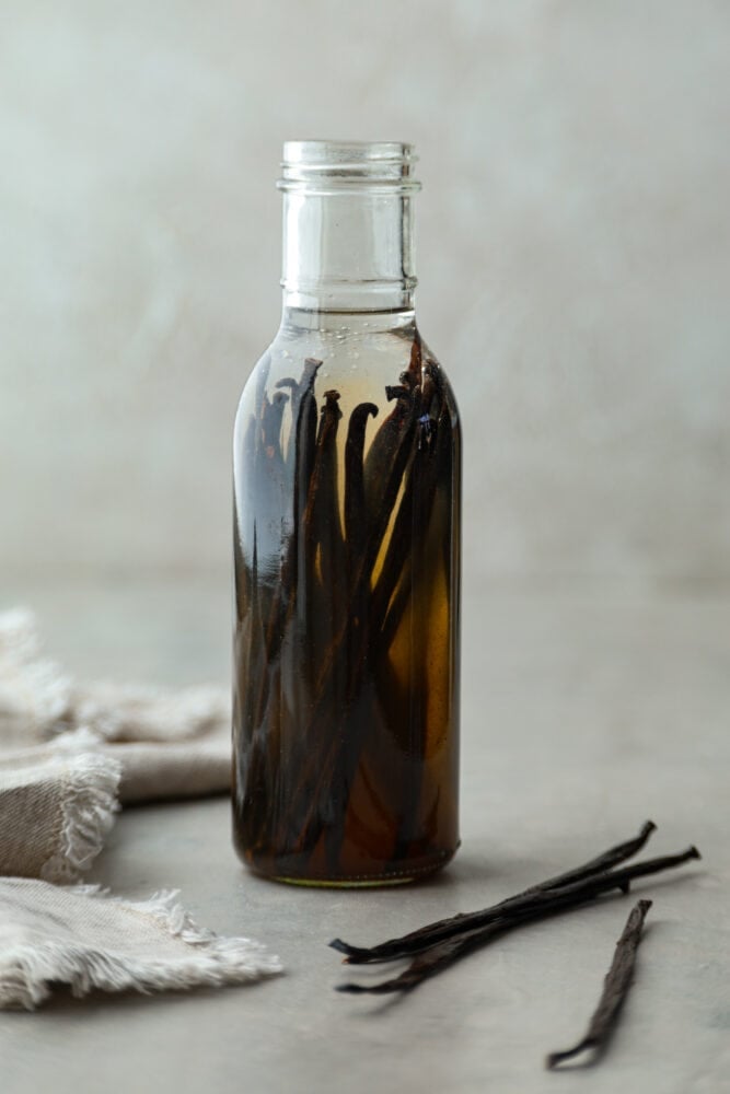 Hero image of vanilla beans in a glass jar being extracted by a clear alcohol.