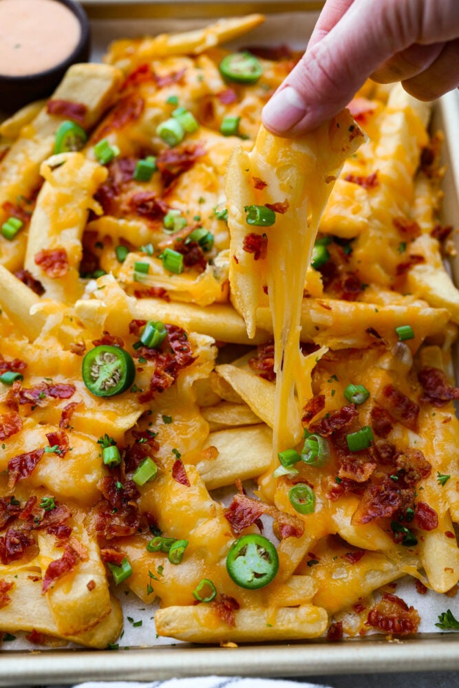 Closeup of a cheese fry being pulled from the pan.