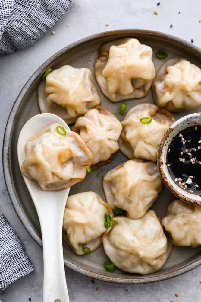 Soup dumplings on a plate with a spoon.