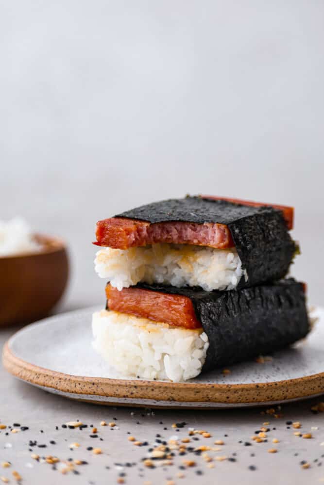 2 musubi on a stoneware plate. One has a bite taken out of it.
