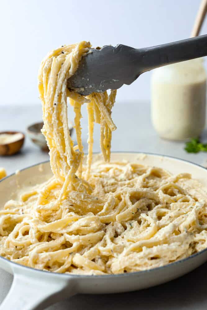 This is the most creamy and delicious homemade alfredo sauce that you will ever make! It's a tried and true recipe that will take all of your favorite pasta dishes to the next level. Using tongs to pick up fettuccine alfredo.