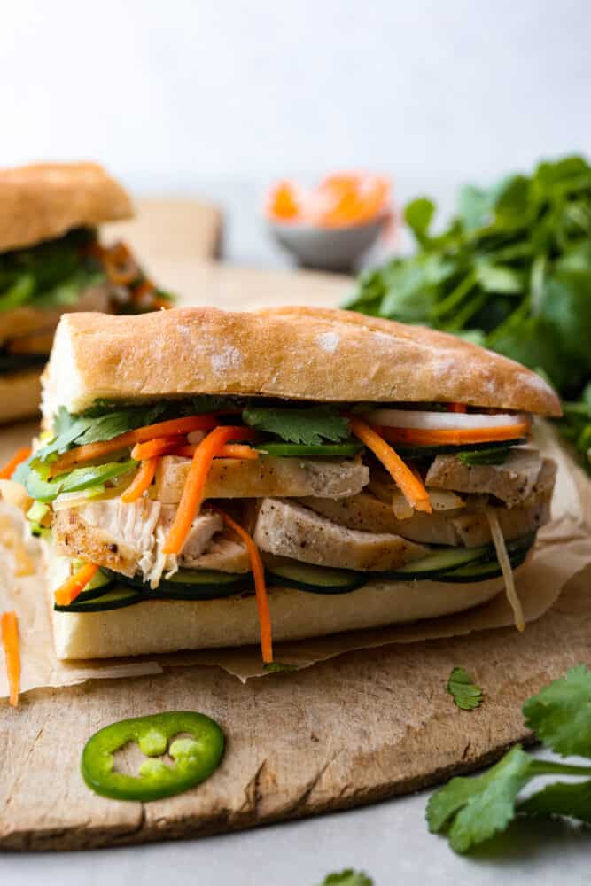 With juicy chicken and tangy pickled veggies sandwiched between two slices of baguette, this recipe inspired by Vietnamese bánh mì is sure to take your lunch game from good to great. It’s a medley of flavors that will have your taste buds singing! One half of a Vietnamese chicken sandwich.