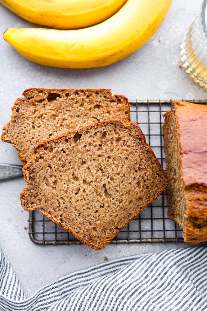 Have you ever tried adding some bubbly goodness to your favorite fruit bread? Well, if you haven't, you're missing out on an amazing treat! This banana beer bread is moist, slightly sweet, with a subtle beer taste that adds a fun twist to the classic banana bread recipe, and the best part? It's super easy to make! Top-down view of 2 slices of bread on a wire cooling rack.