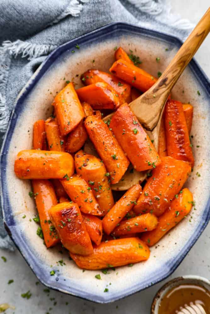 Top-down view of brown butter carrots in a blue and white bowl.