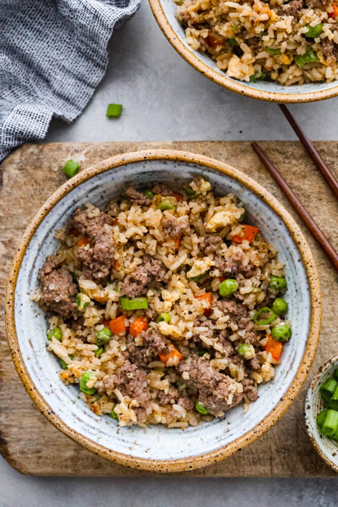 Beef fried rice in a trencher with chop sticks next to it.