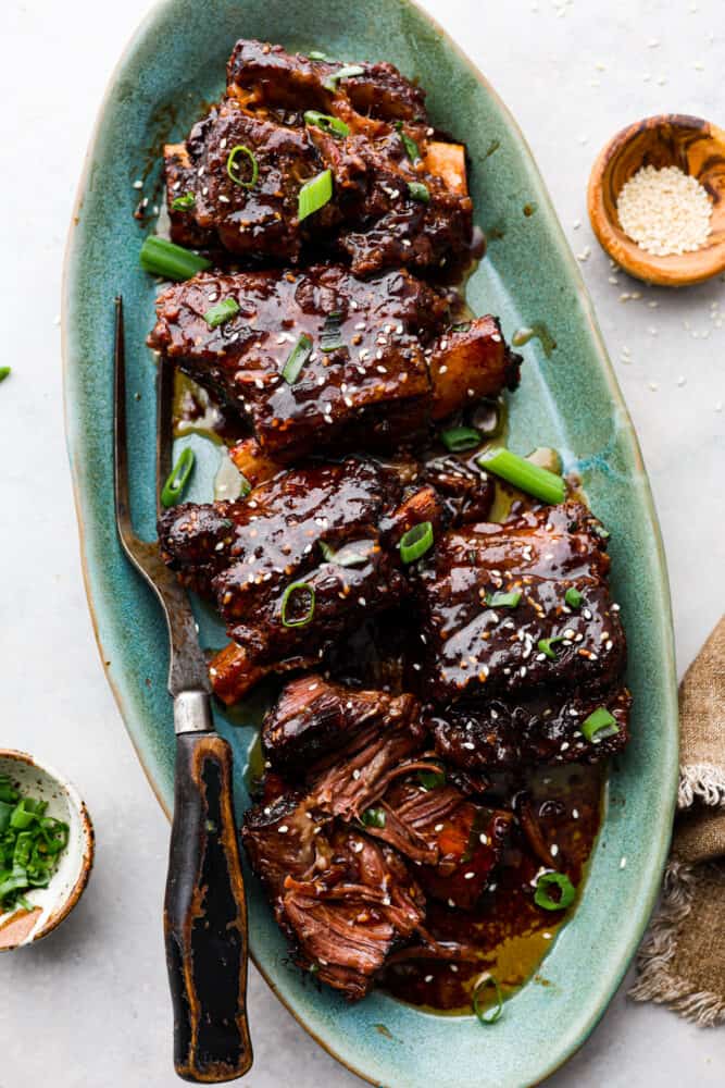 Korean short ribs on a platter with tongs.