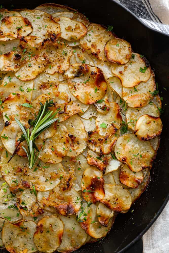 Potato galette is a beautiful side dish made up of thinly sliced potatoes seasoned to perfection and baked until crispy on top and creamy in the middle. They are next-level delicious and really easy to make at home! A close up of potato galette in a cast iron skillet.