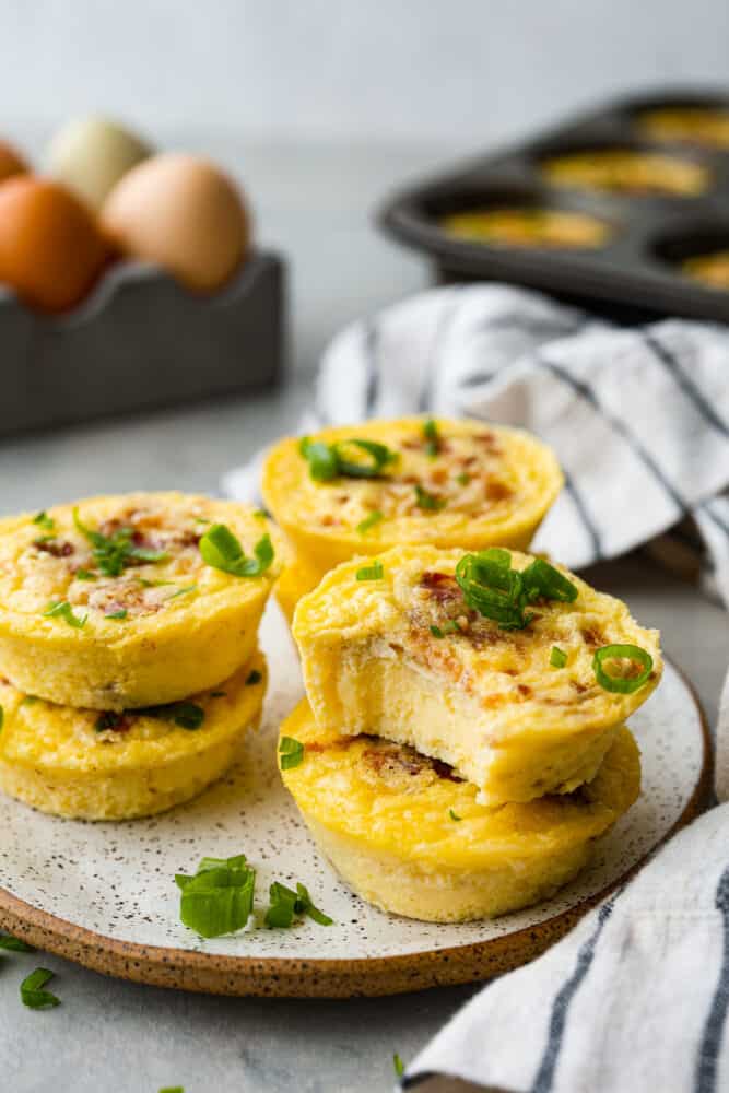 Starbucks egg bites stacked on a plate garnished with green onions.