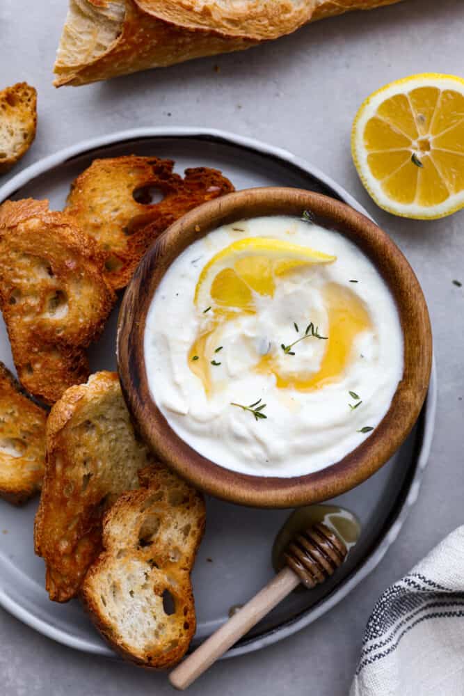 A small bowl of whipped ricotta served with baked slices of baguette.