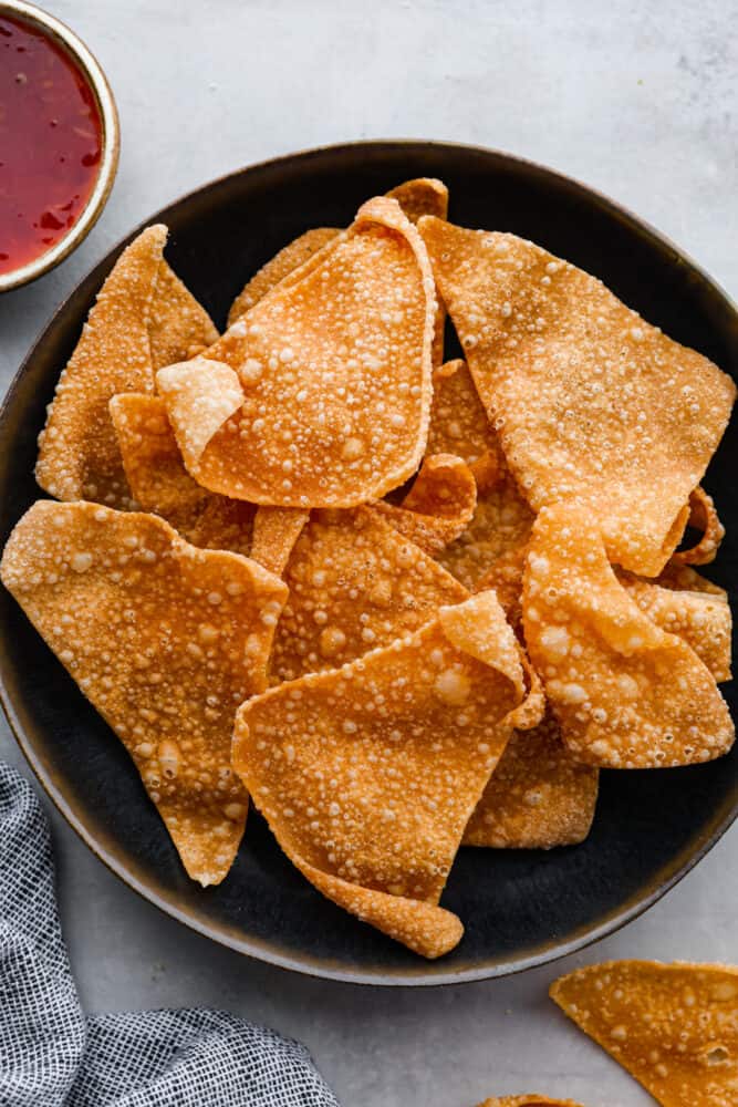 Top-down view of wonton chips in a black bowl.