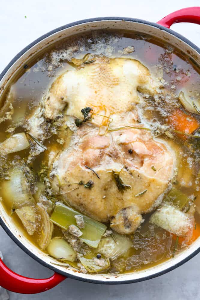 Learning how to boil a whole chicken is a great skill to have in your back pocket, especially if you're trying to eat clean or meal prepping! This boiled chicken is flavorful, juicy, and can easily be transformed into a one-pot meal. A bone-in chicken cooking in broth.