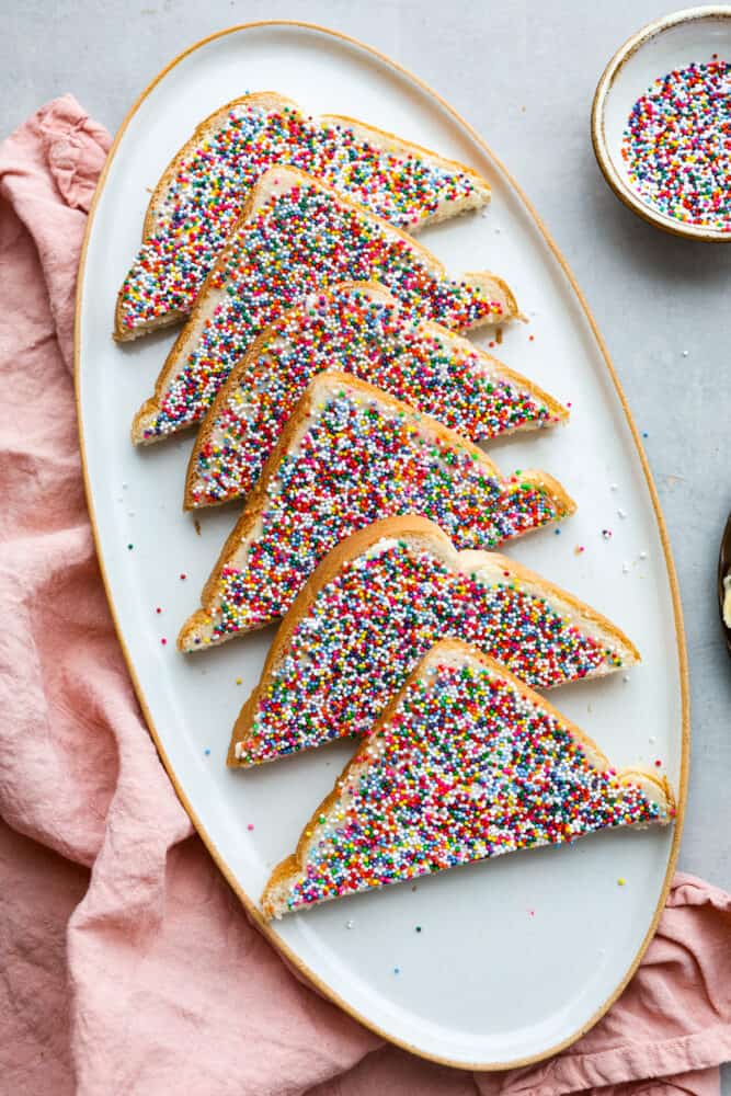 6 slices of fairy bread on a white serving dish.