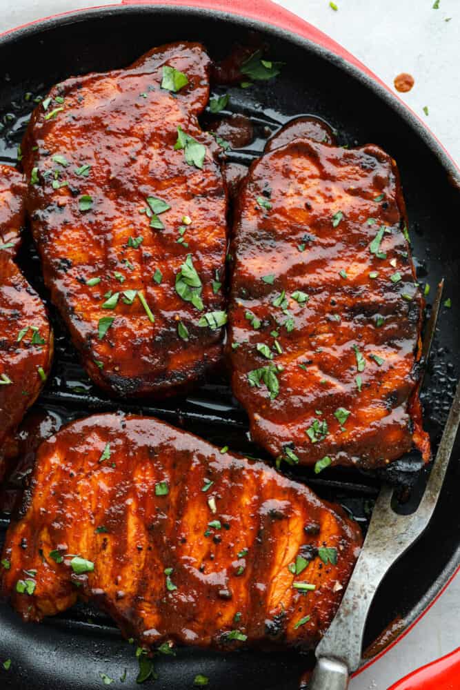 A close up of the post chops in a pan garnished with cilantro. 