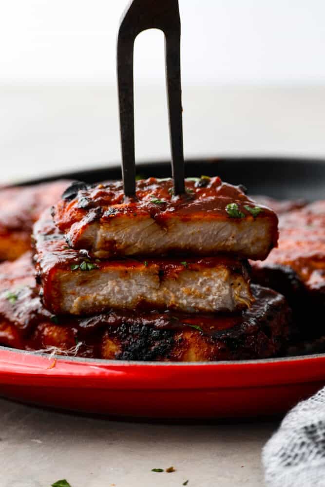 A sliced pork chop with a large carving fork holding the pieces together. 