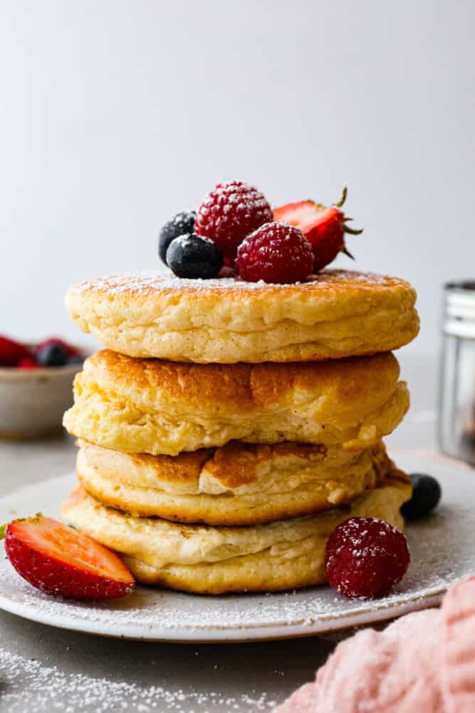 A stack of 4 pancakes, topped with fresh berries.
