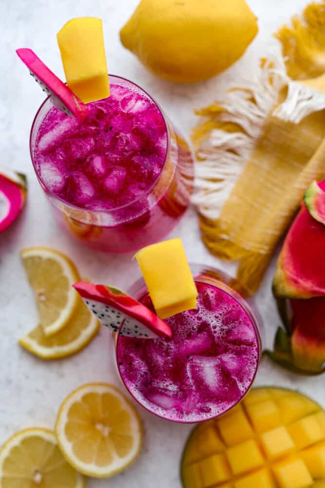 Top-down view of lemonade garnished with slices of mango and dragon fruit.