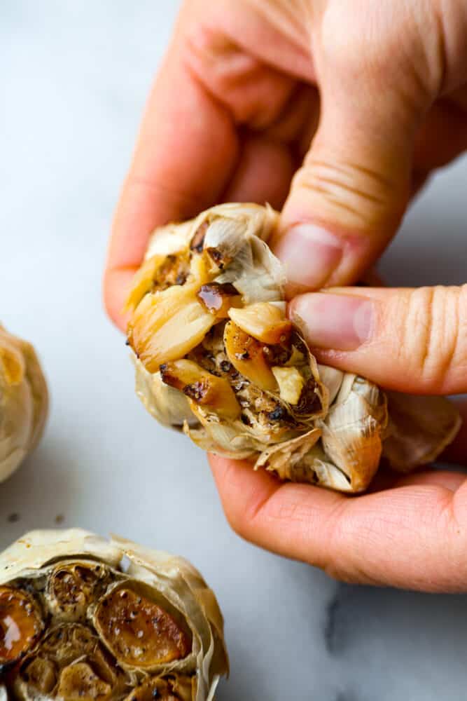 A garlic head being torn open to reveal the cloves inside.