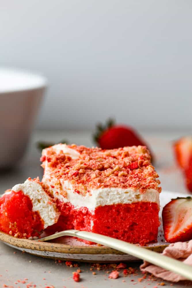 A slice of Strawberry Crunch cake on a plate with a gold fork. 