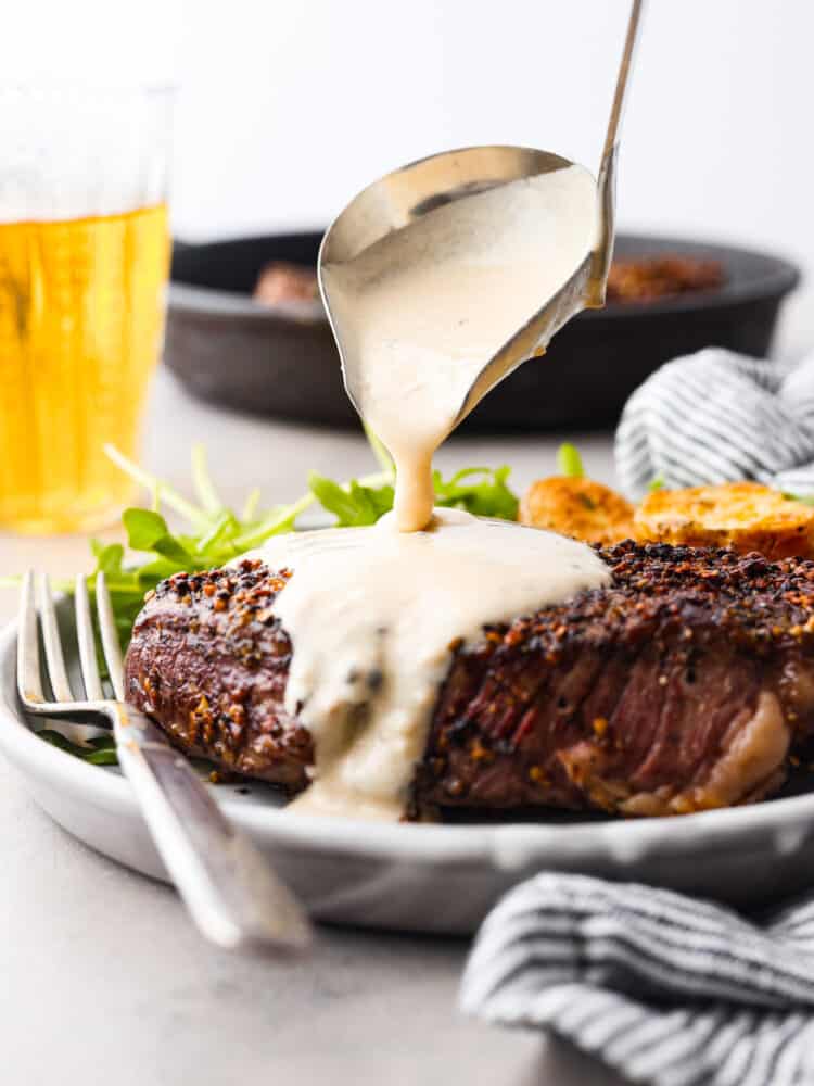 Hero image of a creamy sauce being poured over a steak.